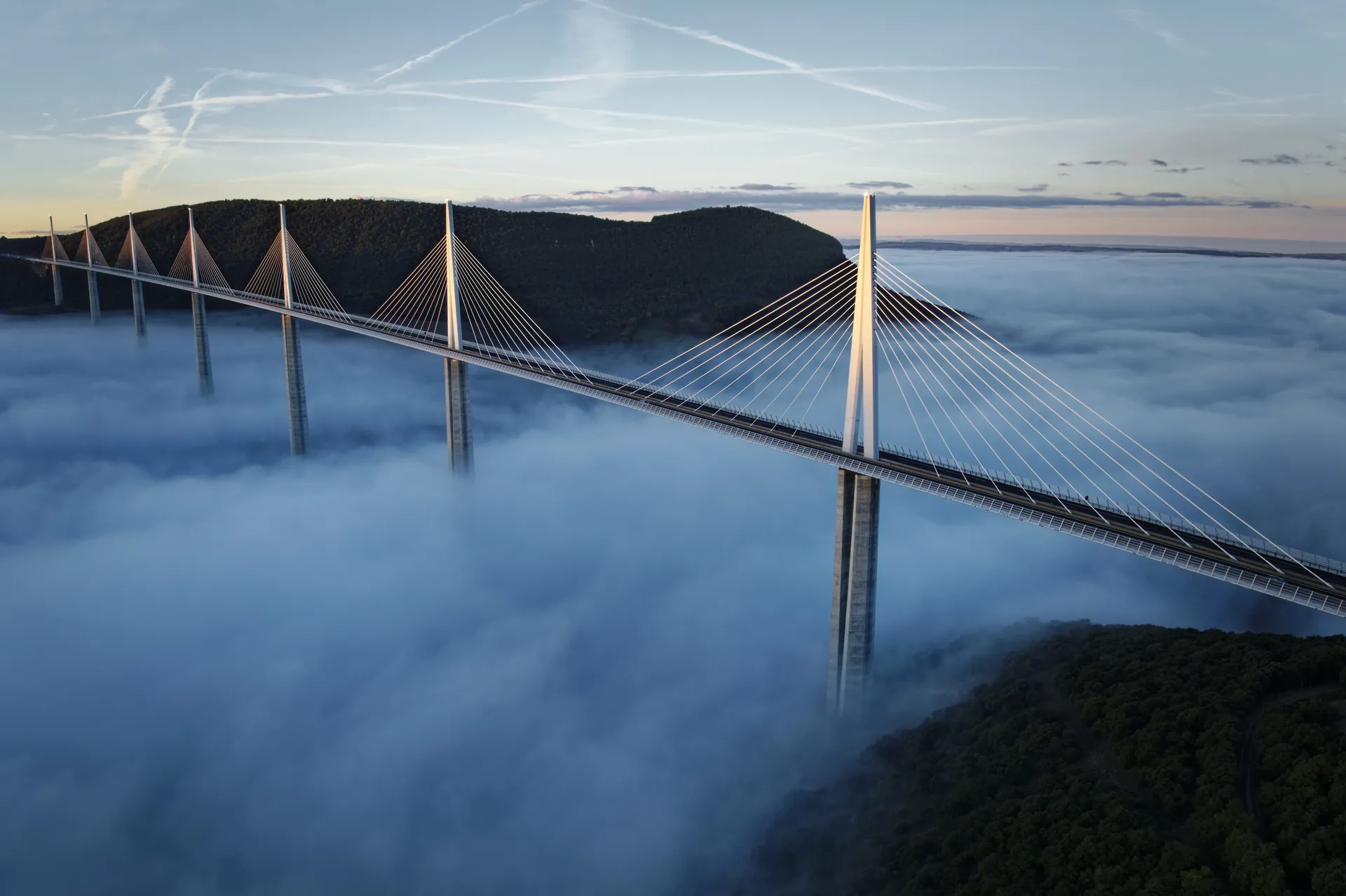 Le viaduc de Millau émergeant d'une mer de nuages au lever du jour