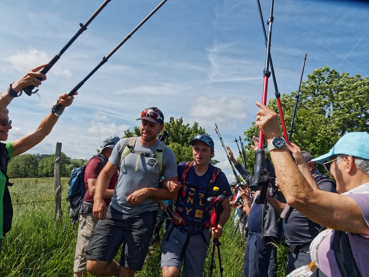Groupe de randonneurs souriants avec leurs bâtons dans un pré